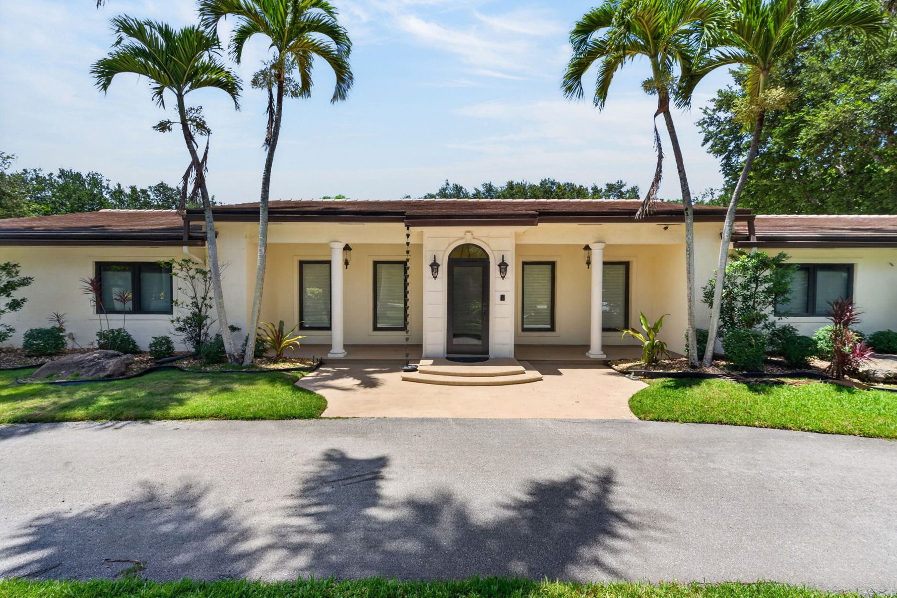 Mediterranean ranch home framed by palms in Pinecrest, Florida