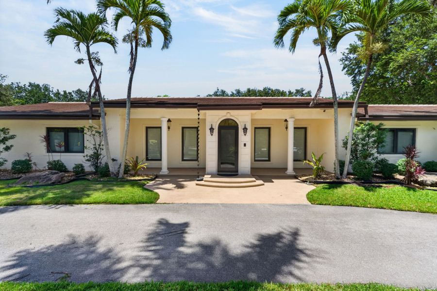 Mediterranean ranch home framed by palms in Pinecrest, Florida