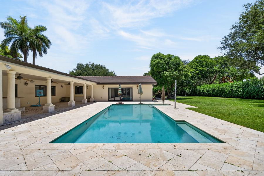 Pool deck and lawn under a blue South Florida sky